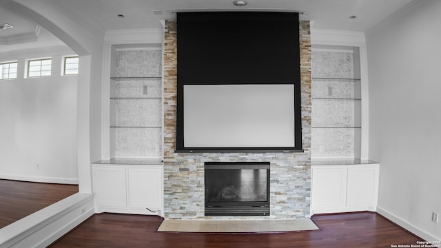 unfurnished living room with crown molding, baseboards, built in shelves, and dark wood-type flooring