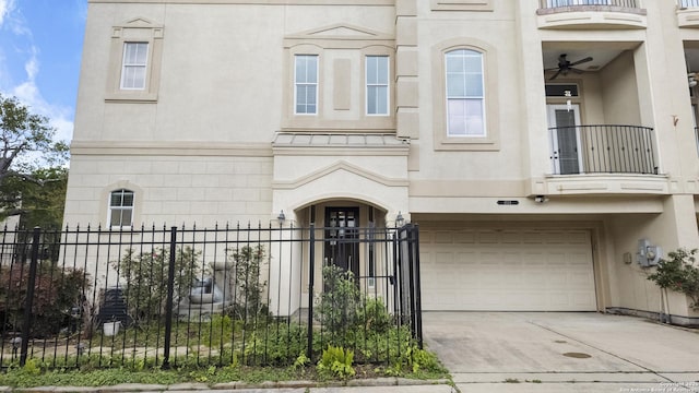 view of front of home with stucco siding, concrete driveway, fence private yard, and a balcony
