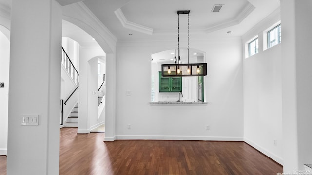unfurnished dining area with visible vents, crown molding, stairs, wood finished floors, and a raised ceiling