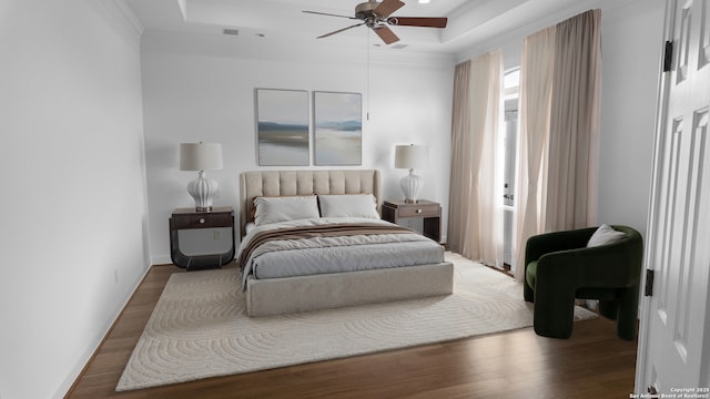 bedroom with crown molding, ceiling fan, wood finished floors, and a raised ceiling
