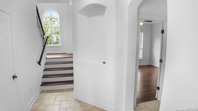 staircase with crown molding, baseboards, and arched walkways