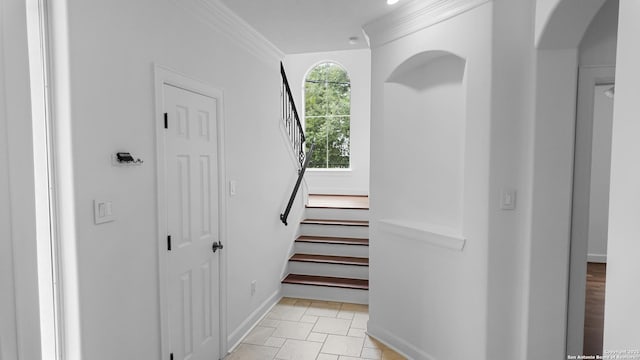 staircase with crown molding, arched walkways, and baseboards