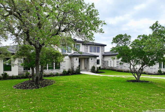 view of front of property with a front lawn, stucco siding, and stone siding