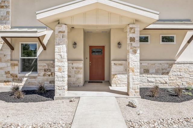 view of exterior entry with stone siding and stucco siding