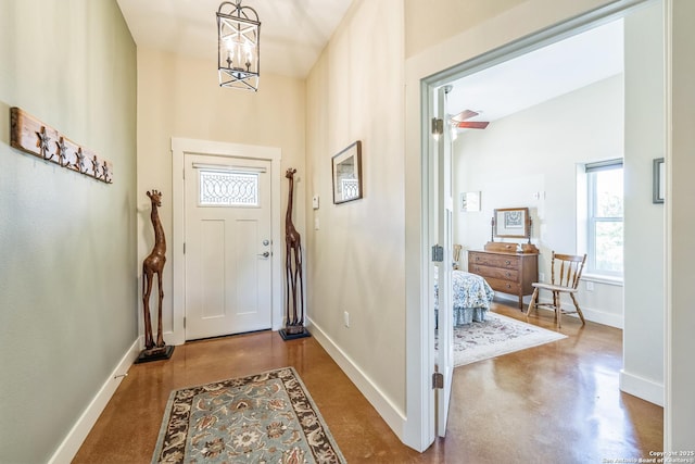 entrance foyer featuring a high ceiling, concrete flooring, a chandelier, and baseboards