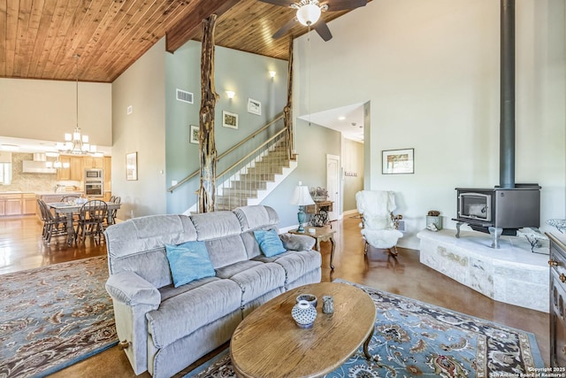 living room featuring high vaulted ceiling, stairs, a wood stove, wooden ceiling, and visible vents