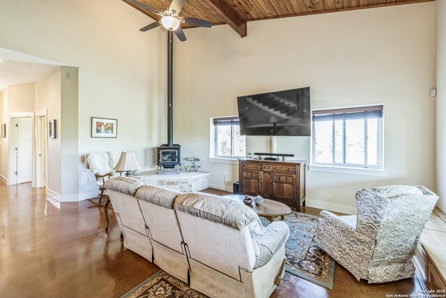 living room with wood ceiling, concrete floors, high vaulted ceiling, a ceiling fan, and a wood stove