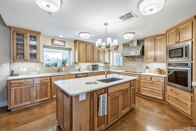 kitchen with visible vents, a sink, appliances with stainless steel finishes, and wall chimney range hood