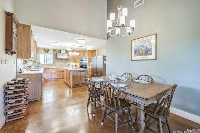 dining area with a towering ceiling, visible vents, concrete flooring, baseboards, and a notable chandelier