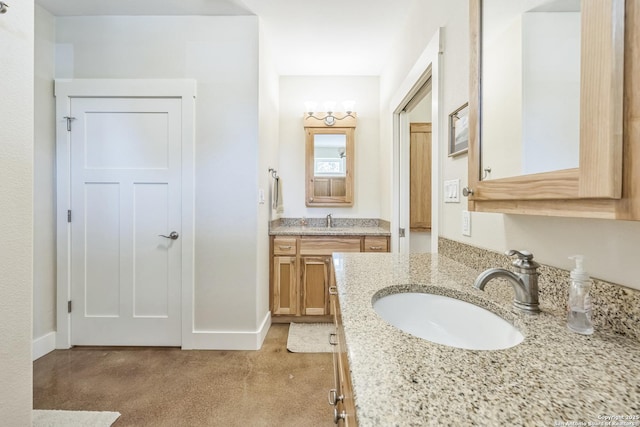 bathroom featuring baseboards, two vanities, and a sink