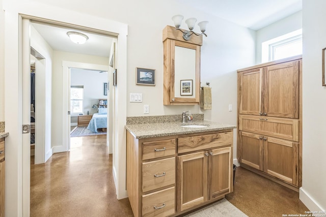 bathroom featuring finished concrete flooring, a healthy amount of sunlight, vanity, and baseboards