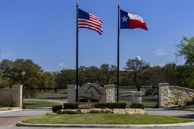 community / neighborhood sign featuring fence and a gate