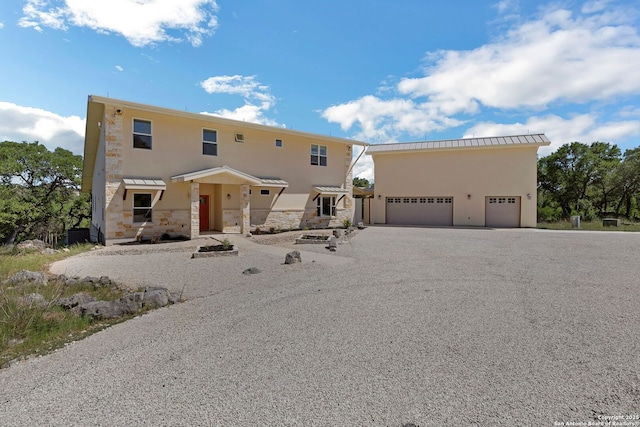 view of front of house with an attached garage, stone siding, stucco siding, and aphalt driveway