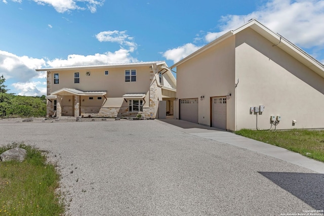 exterior space with stone siding, driveway, a garage, and stucco siding