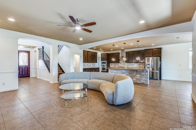 6222 Amber Rose, San Antonio, TX 78253 - living room featuring arched walkways, baseboards, stairway, ceiling fan, and light tile patterned floors