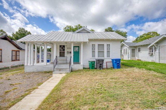 bungalow-style house with metal roof, a standing seam roof, a front lawn, and covered porch