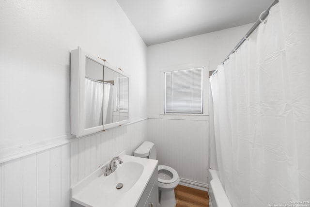 bathroom with wood finished floors, toilet, vanity, and a wainscoted wall