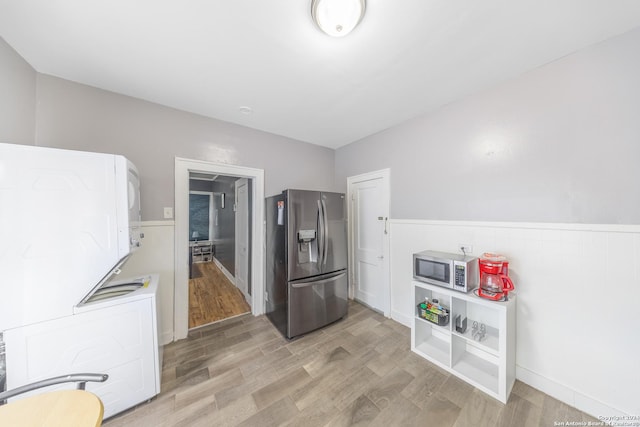 kitchen featuring stacked washer and dryer, light wood-style flooring, and appliances with stainless steel finishes