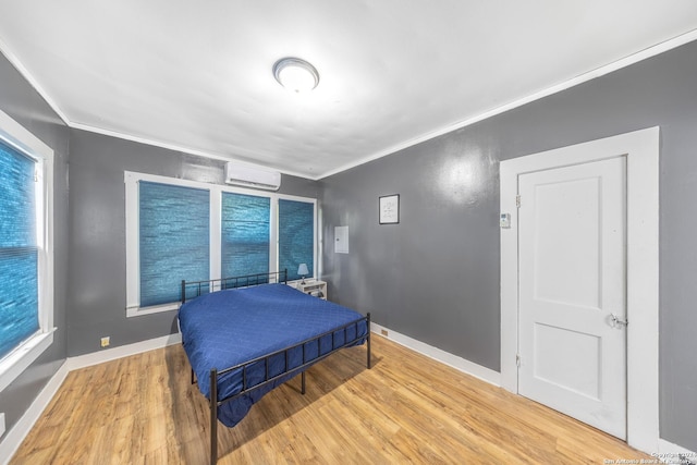 bedroom featuring wood finished floors, an AC wall unit, baseboards, and ornamental molding