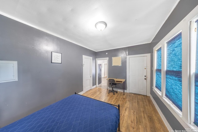 bedroom featuring wood finished floors, crown molding, and baseboards