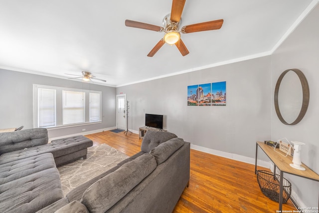 living room featuring wood finished floors, crown molding, baseboards, and ceiling fan