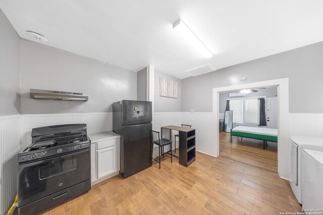kitchen with a wainscoted wall, separate washer and dryer, light countertops, under cabinet range hood, and black appliances