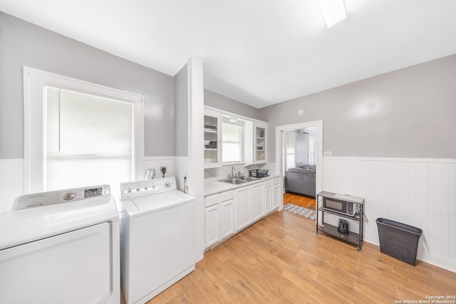 washroom with a sink, wainscoting, light wood-style floors, washing machine and dryer, and laundry area