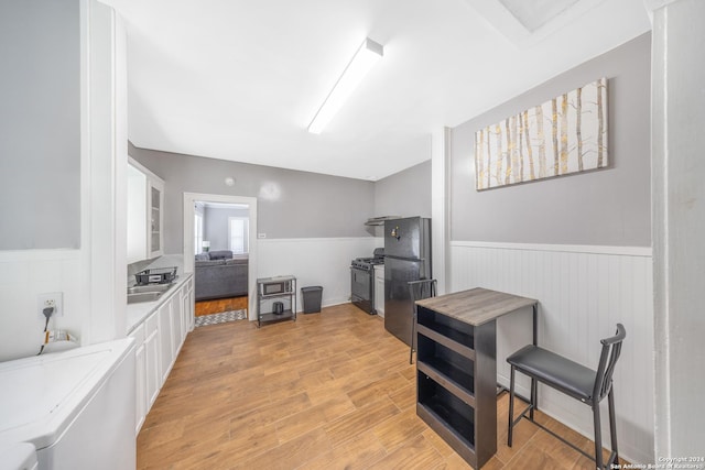 kitchen featuring light countertops, wainscoting, white cabinetry, and black appliances