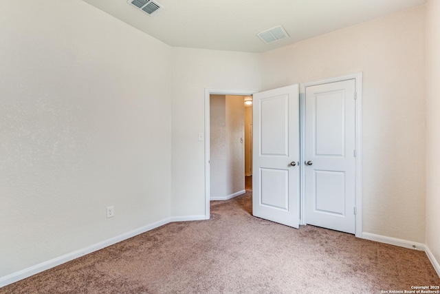 unfurnished bedroom featuring baseboards, visible vents, and light carpet