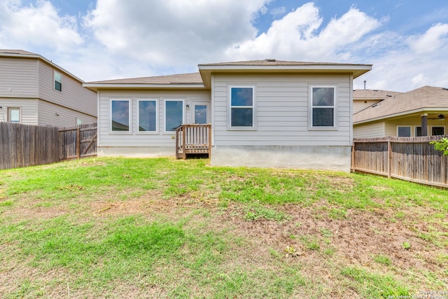 back of house with a fenced backyard and a yard