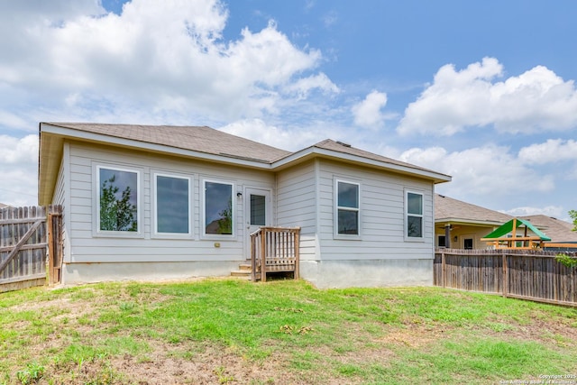 back of property featuring fence and a yard