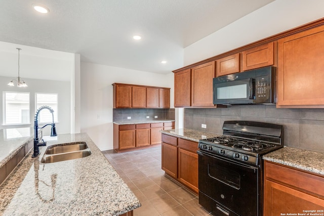 kitchen with brown cabinetry, decorative backsplash, light stone counters, a sink, and black appliances
