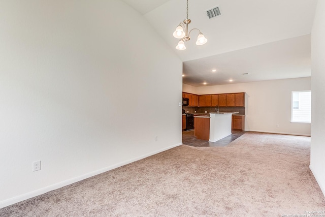 kitchen with brown cabinets, light colored carpet, black microwave, a chandelier, and open floor plan