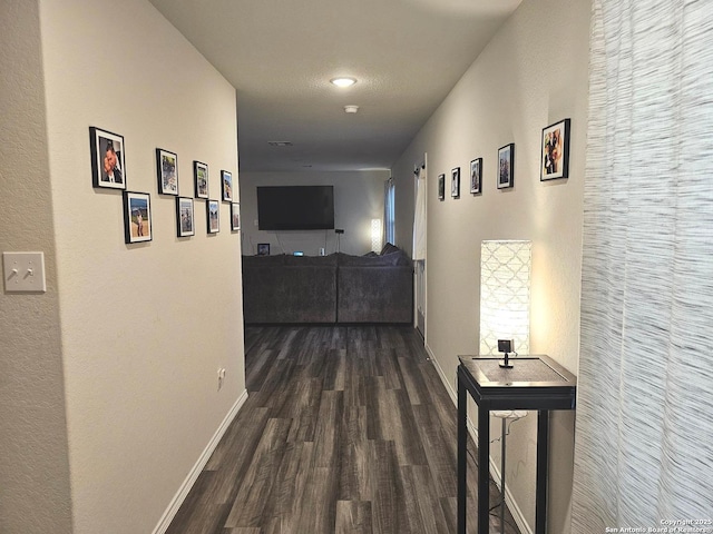 corridor featuring dark wood finished floors and baseboards