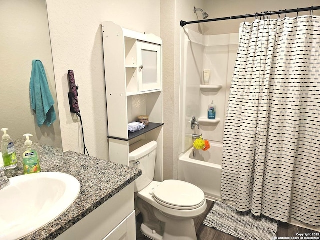 full bath featuring toilet, wood finished floors, shower / bathtub combination with curtain, a textured wall, and vanity