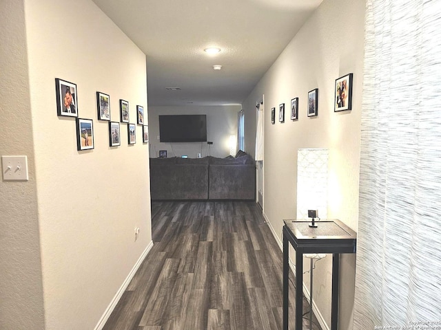 corridor featuring baseboards and dark wood-style flooring