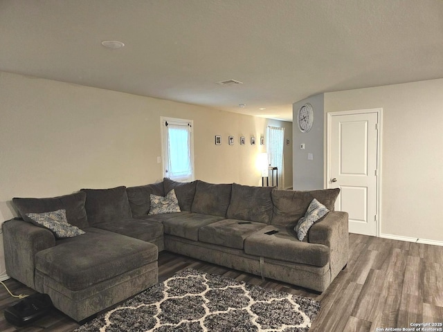 living room featuring wood finished floors, visible vents, and baseboards