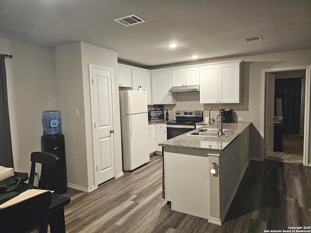 kitchen featuring a sink, visible vents, freestanding refrigerator, stainless steel range with electric stovetop, and under cabinet range hood