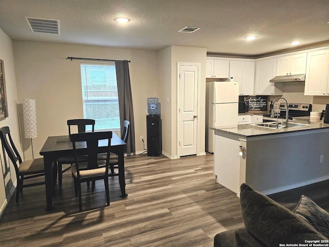 kitchen with visible vents, a sink, freestanding refrigerator, dark wood-style flooring, and white cabinetry