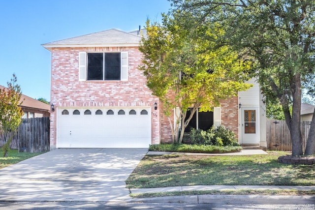 traditional-style house with driveway, fence, a garage, brick siding, and a front yard