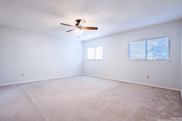 spare room featuring ceiling fan, light carpet, a textured ceiling, and baseboards