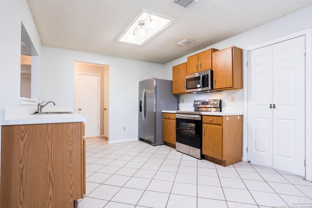 kitchen with stainless steel appliances, visible vents, a sink, and brown cabinets