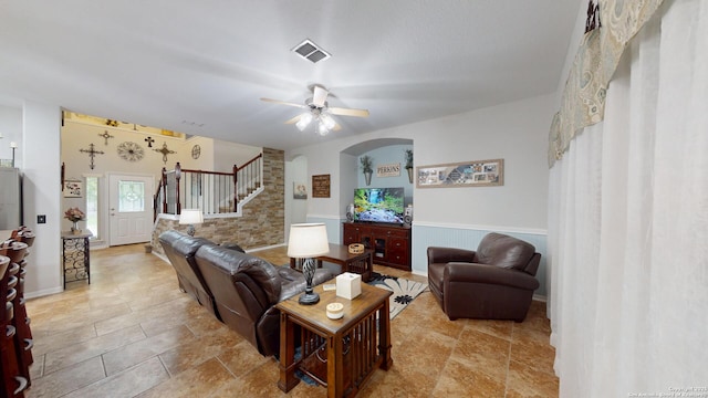 living room featuring arched walkways, stairway, visible vents, and ceiling fan