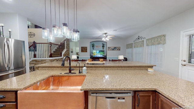 kitchen with stainless steel appliances, open floor plan, light stone counters, ceiling fan, and decorative light fixtures