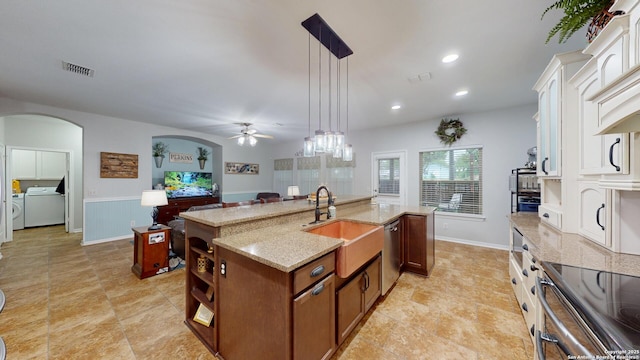 kitchen with a ceiling fan, arched walkways, a center island with sink, appliances with stainless steel finishes, and visible vents