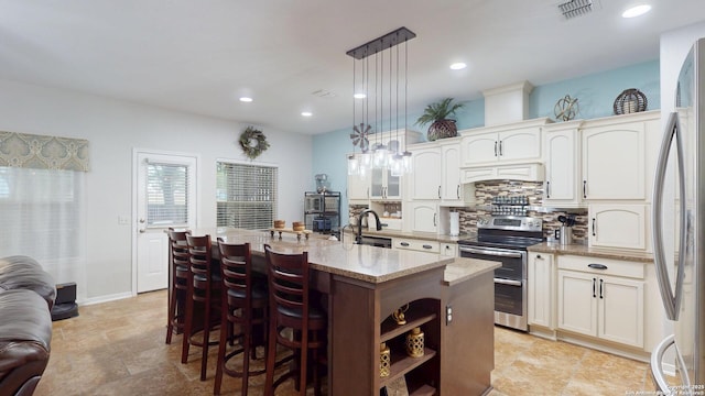 kitchen featuring tasteful backsplash, an island with sink, stainless steel appliances, a kitchen bar, and visible vents