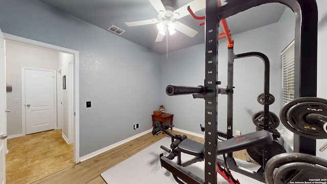 workout room with light wood-type flooring, ceiling fan, arched walkways, baseboards, and visible vents