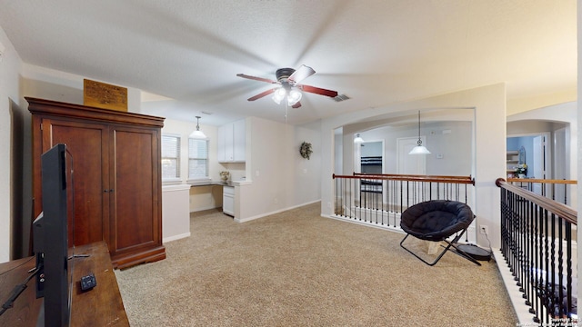 living area with visible vents, a ceiling fan, light carpet, arched walkways, and baseboards