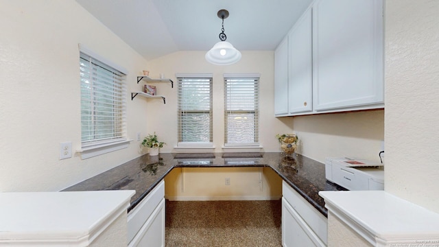 kitchen with lofted ceiling, dark stone countertops, white dishwasher, pendant lighting, and white cabinetry