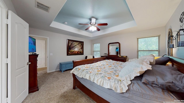 bedroom with light carpet, baseboards, visible vents, a ceiling fan, and a raised ceiling